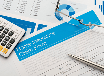Home insurance claim form with a calculator, pen and glasses laying on top
